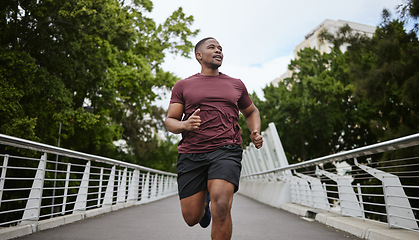 Image showing Fitness, exercise and black man running in city for health and wellness. Sports, runner or young male from Nigeria jog, exercising and cardio workout outdoors on bridge training for marathon practice