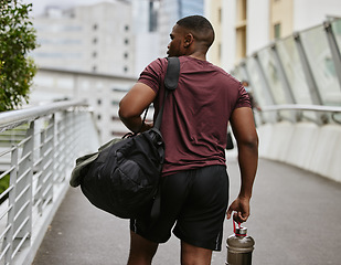 Image showing Black man, back or fitness bag on city bridge, road or street with workout gear, training water bottle or exercise kit. Runner, sports athlete or personal trainer in urban travel to gym for wellness