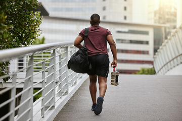 Image showing Fitness, city or black man walking to gym on a bridge with a sports bag or water bottle for a workout or exercise. Back view, motivation or healthy person traveling to a training center or club