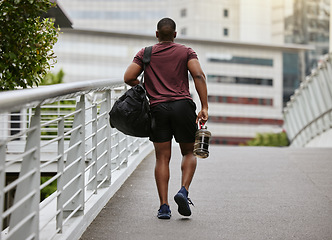 Image showing Fitness, health and man walking to gym with bag and water bottle ready for training or exercise workout. Motivation, bodybuilding and sports, strong black man athlete on street in city with gym bag.