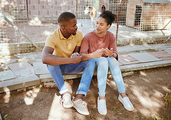 Image showing Black couple, sit and love in animal shelter, homeless canine center or foster care kennel in adoption decision choice. Talking, black woman and bonding man in pet dog charity or volunteer community