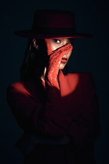 Image showing Beauty, fashion and aesthetic woman in dark studio with spotlight on eye, face or head for makeup, cosmetics and show girl portrait. Female model with lace gloves and red clothes for retro 90s style