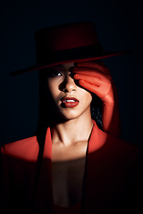 Image showing Fashion, beauty and spotlight on face of woman for creative, makeup and art with shadow. Designer, luxury and retro with mystery girl model in red suit for magic, privacy and dramatic in studio