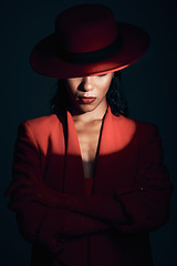 Image showing Fashion, red suit with spotlight for woman in dark, mystery and 90s retro on a black studio background. Designer, power and model with vintage clothes, arms crossed and makeup for empowerment