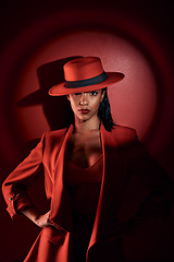 Image showing Spotlight, red suit and woman with fashion from 90s, elegant clothes and vintage on a studio background. Creative, dark and portrait of a retro, confident and classy model with a sexy aesthetic