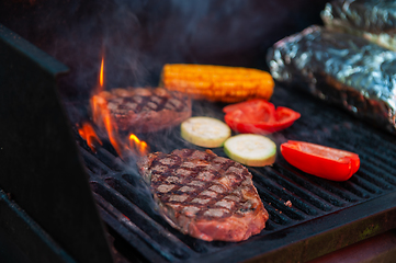 Image showing Beef steaks on the grill with flames