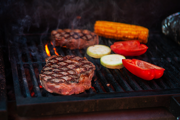 Image showing Beef steaks on the grill with flames