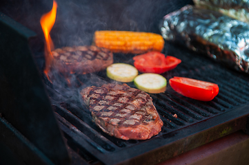 Image showing Beef steaks on the grill with flames