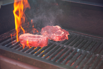 Image showing Beef steaks on the grill with flames