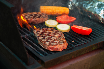 Image showing Beef steaks on the grill with flames