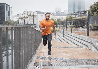 Image showing City fitness, man and running in rain for exercise, body workout and cardio training. Portrait, wet and urban runner with focus, motivation and strong motivation for sports, power and marathon energy