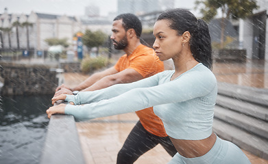 Image showing Workout, stretching and couple of friends training with focus before running in the rain. Urban, runner athlete and sports exercise in winter of black people with motivation in the city for fitness