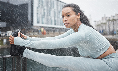 Image showing Fitness, rain or black woman stretching in city of London to start running exercise, workout or cardio training. Portrait, mindset or healthy girl athlete runner in sports warm up on a street or road