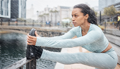 Image showing Fitness, rain and woman stretching outdoor for muscle wellness, health and energy in winter with workout, running or training. City, Amsterdam and sports runner with legs exercise, cardio and workout