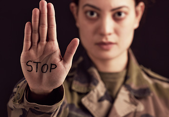 Image showing Stop, war and hand of a military woman angry, frustrated and with sign against a dark black studio background. Army, anger and portrait of a soldier with body language and message to end a battle