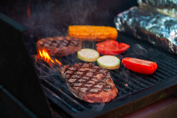 Image showing Beef steaks on the grill with flames