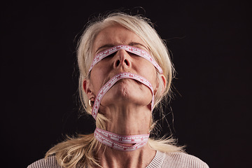 Image showing Anorexia, tape measure and face of woman with eating disorder in studio on a dark background. Mental health, bulimia and depression of mature female with facial measuring tape and weight loss problem