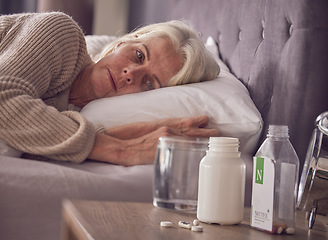 Image showing Elderly woman, bed and medical addiction with pills, medicine or medication while lying awake at home. Senior female suffering from sick, illness or mental health, trauma or disorder in the bedroom