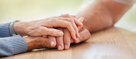 Image showing Senior, holding hands and support with couple, comfort and help on table for grief, pain or sympathy. Elderly man, old woman and helping hand for empathy, love and care in home with bonding together