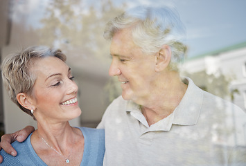 Image showing Love, hug and window with senior couple, smile and retirement for bonding, romance and relationship. Romantic, man and woman embrace, marriage and happiness for intimate quality time and glass.