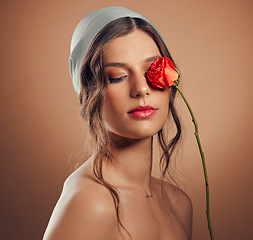 Image showing Flowers, thinking and woman with makeup beauty, floral wellness and creative on a brown studio background. Peace, flower and model with a rose for creativity, luxury aesthetic and idea for cosmetics