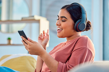 Image showing Woman on couch, smartphone and headphones for music, audio and connectivity in lounge. Hispanic female, girl and headset for radio, podcast and streaming to listen, social media, connect or happiness