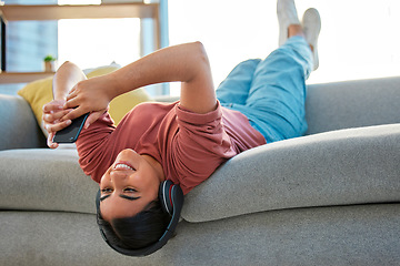 Image showing Headphones, phone and woman upside down on sofa in home streaming music, radio or podcast. Relax, mobile and happy female on couch with smartphone on social media, texting or web browsing in house.