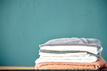 Image showing Bathroom, laundry and stack of towels on blue background for cleaning, washing and body hygiene at home. Fabric, textiles and pile of fresh, soft and clean linen for shower, bath and spa wellness