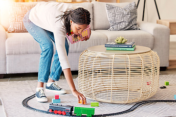 Image showing Spring cleaning, living room and kid toys cleaning of a mother of maid in a home. House worker, mom and clean service with a black woman in a lounge picking op children toy train on the floor carpet