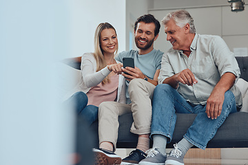 Image showing Phone, relax and family on a sofa in the living room networking on social media, mobile app or the internet. Happy, smile and couple helping a senior man with his cellphone at his home in Canada.