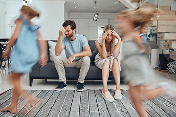 Image showing Kids running, parents on sofa tired and chaos in living room with frustrated mom and dad burnout. Happy children, parenting stress and excited girl and boy with energy play, woman and man in crisis