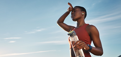 Image showing Water bottle, tired and black woman on break after running, exercise or cardio workout with low angle and mock up. Sports, fitness and sweating female holding liquid for hydration after training.
