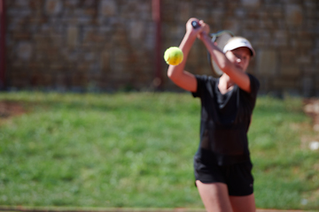 Image showing A young girl showing professional tennis skills in a competitive match on a sunny day, surrounded by the modern aesthetics of a tennis court.