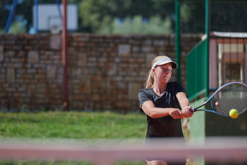 Image showing A young girl showing professional tennis skills in a competitive match on a sunny day, surrounded by the modern aesthetics of a tennis court.