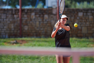 Image showing A young girl showing professional tennis skills in a competitive match on a sunny day, surrounded by the modern aesthetics of a tennis court.