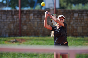 Image showing A young girl showing professional tennis skills in a competitive match on a sunny day, surrounded by the modern aesthetics of a tennis court.