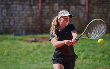 Image showing A young girl showing professional tennis skills in a competitive match on a sunny day, surrounded by the modern aesthetics of a tennis court.