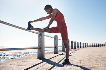 Image showing Black woman, legs or fitness stretching by beach, ocean or sea for muscle pain relief, healthcare wellness or marathon ready. Runner, sports athlete or warm up exercise for promenade workout training