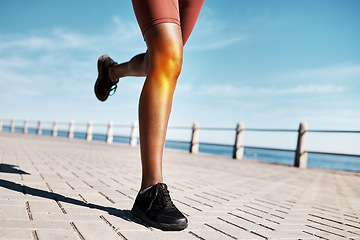 Image showing Black woman runner, knee pain and legs by promenade, street or training by ocean in fitness, speed or health. Feet, sneakers and running on road by sea for wellness, nature workout or summer exercise