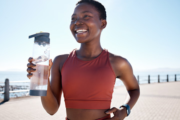 Image showing Drinking water, fitness and black woman running by the sea for sport, training and exercise workout. Relax, freedom and sports smile of a runner athlete happy about cardio, energy and health wellness