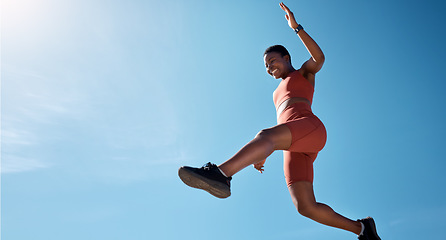 Image showing Sports, fitness and black woman jumping with blue sky background from below. Running, exercise and jump, woman training for health goals, motivation and wellness with happy smile and mockup in summer