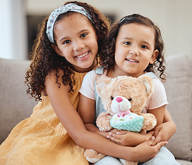 Image showing Family, children hug and portrait of girls on sofa in living room while holding teddy bear. Love, care and happy kids, sisters and siblings bonding, embrace and hugging on couch in lounge of house.