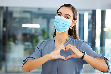 Image showing Covid, employee or woman with heart sign or hand gesture in office building showing support, love or safety. Compliance, coronavirus or happy worker in face mask with peace, wellness or care at job