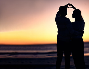 Image showing Couple, silhouette and sunset beach with heart shape hands for love, commitment and care on a romantic date, holiday or honeymoon at sea. Man and woman together on ocean vacation for nature travel