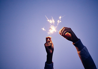 Image showing Sparkler, hand and person at night for new years eve celebration with bright, burning fun to celebrate. Celebrating, sparkle and blue nighttime background with a firework or firecracker in hands