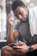 Image showing Gym, workout and tired black man with phone for social media and towel for sweat from cardio. Fitness, rest and exercise fatigue of sweaty guy on smartphone app for body relaxation to recover.