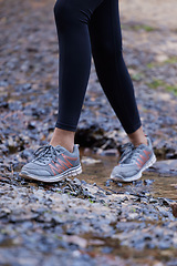 Image showing Woman, running shoes and feet in mud while hiking in nature for fitness, exercise and cardio training outdoor for health, travel and wellness on adventure. Legs of female athlete walking forest path