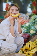 Image showing Asian woman, portrait and fruit or vegetable market outdoor for grocery shopping, food supermarket and happy customer with banana. Nutrition, grocery store fruits and happiness for healthy eating