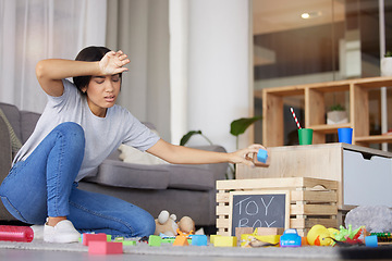 Image showing Toys, mother tired and headache for cleaning, messy living room and exhausted. Woman, clean playthings and female stress, frustrated and upset in lounge, annoyed and overworked in home with disorder.