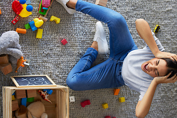 Image showing Tired, stress and frustrated mom with fatigue and headache cleaning children toys. Above view of mama and woman scream from kids mess in a home living room feeling overwhelmed burnout from motherhood